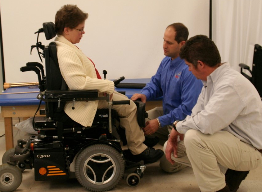 A woman meets with her clinician and supplier to assess the fit of her new wheelchair.
