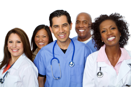 A group of female and male doctors of different ethnicities stand together in lab coats smiling.