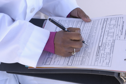 A seated doctor fills out a prescription form.