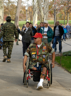 A military veteran navigates a crowded park in his manual wheelchair.